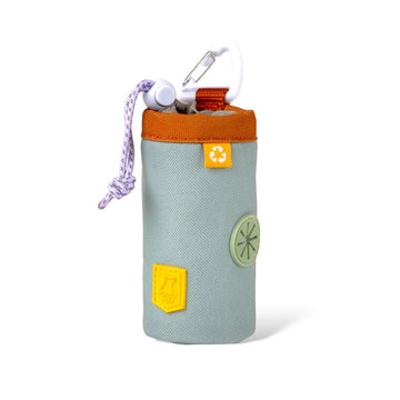 The Alpha 360 Dog Poop Bag Holder Glacier Green is a small, cylindrical, light gray pouch with an orange zipper, rope handle, metal clip, yellow and green patches, and a recycling symbol on the front.