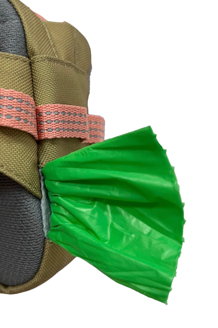 Green plastic bag partially pulled from a pouch with tan and pink webbing straps on white background.