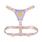 Pastel-colored adjustable pet harness with beige, purple, and pink straps and plastic buckles, laid flat on white.