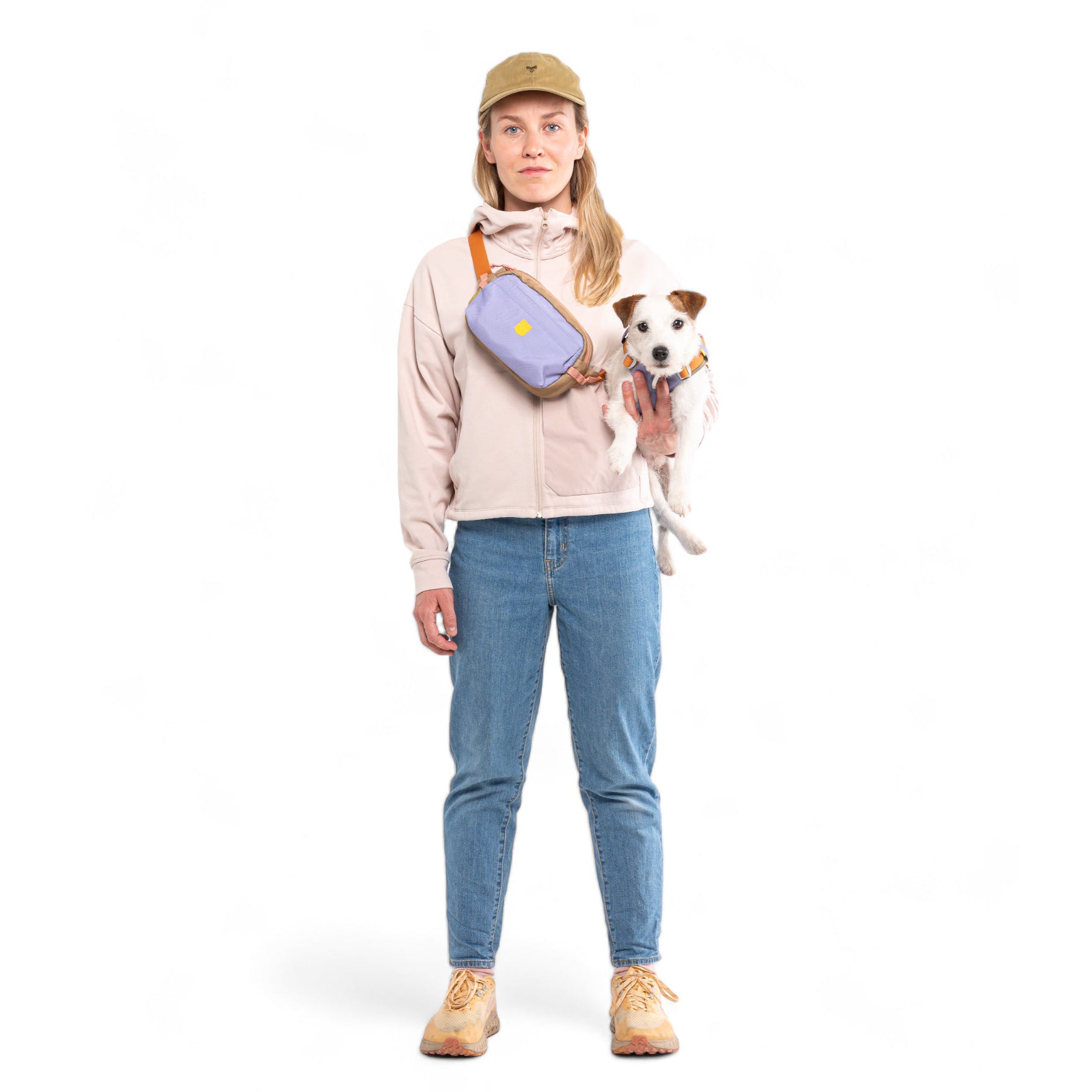 Woman in a pink hoodie and jeans holding a white dog with brown spots.