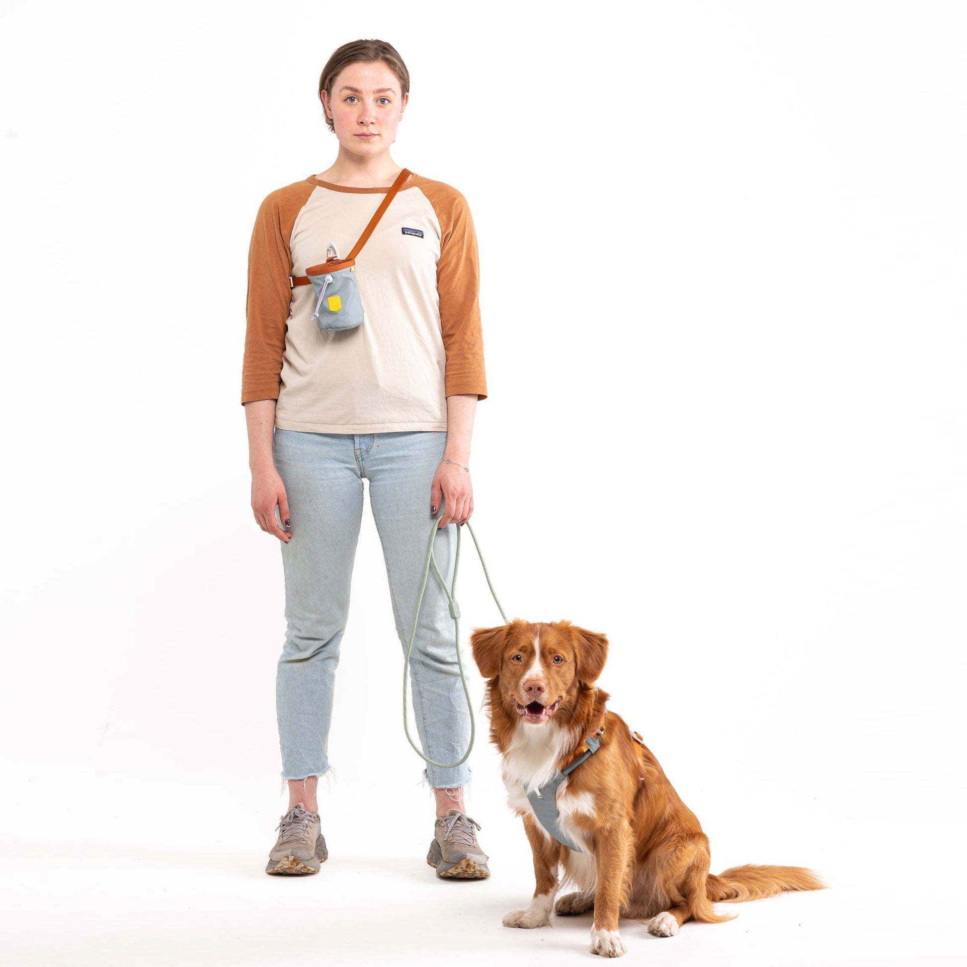 A woman and her dog pose for a photo with a white background.